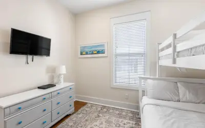 a bedroom with a bed and a dresser with a flat screen tv at Beach Dreamer by Oversee 30A in Seacrest