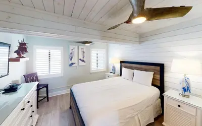 a bedroom with a bed and a desk and windows at Beach Pleeze by Oversee 30A in Panama City Beach