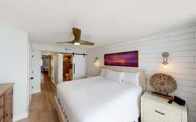 a bedroom with a white bed and a ceiling fan at Beach Pleeze by Oversee 30A in Panama City Beach