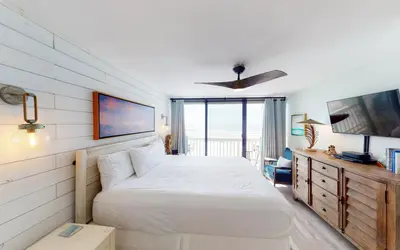 a bedroom with a white bed and a television at Beach Pleeze by Oversee 30A in Panama City Beach