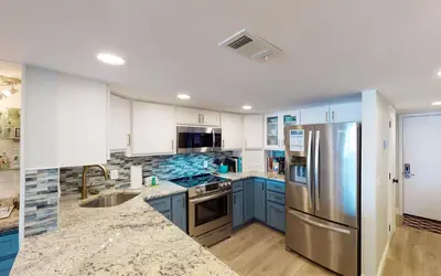 a kitchen with blue cabinets and a stainless steel refrigerator at Beach Pleeze by Oversee 30A in Panama City Beach