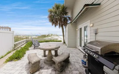 a patio with a grill and a table and chairs at Beachfront Oasis by Oversee 30A in Panama City Beach