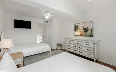 a white bedroom with a bed and a dresser at Beachfront Oasis by Oversee 30A in Panama City Beach