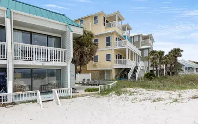 a building on the beach next to the sand at Beachfront Oasis by Oversee 30A in Panama City Beach