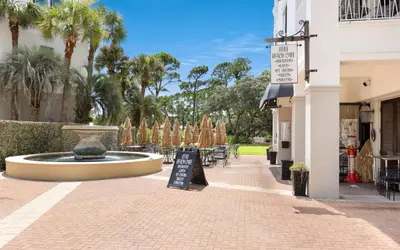 a courtyard with a fountain and tables and palm trees at Bimini by Oversee 30A in Carillon Beach
