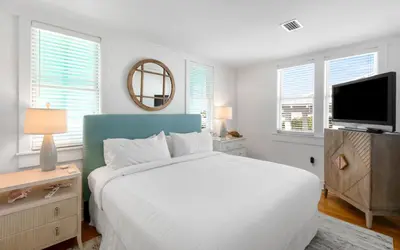 a white bedroom with a bed and a tv at Peaceful Easy Feeling by Oversee 30A in Carillon Beach