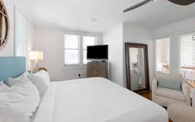 a white bedroom with a bed and a tv at Peaceful Easy Feeling by Oversee 30A in Carillon Beach