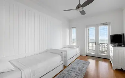 a white bedroom with a bed and a ceiling fan at Peaceful Easy Feeling by Oversee 30A in Carillon Beach
