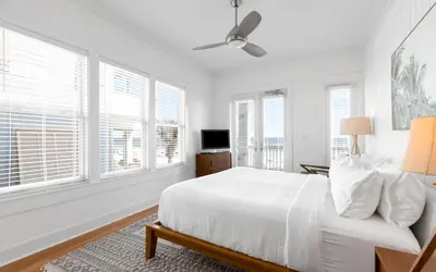 a white bedroom with a white bed and windows at Peaceful Easy Feeling by Oversee 30A in Carillon Beach