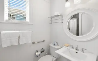 a white bathroom with a sink and a mirror at Peaceful Easy Feeling by Oversee 30A in Carillon Beach