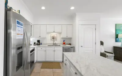 a kitchen with white cabinets and a stainless steel refrigerator at Seagrove Villa B202 by Oversee 30A in Santa Rosa Beach