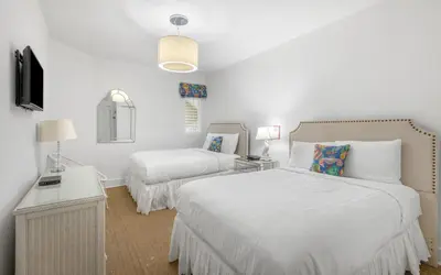a white bedroom with two beds and a tv at Seagrove Villa B202 by Oversee 30A in Santa Rosa Beach