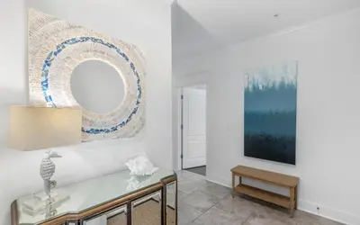 a living room with a glass table and a mirror at Seagrove Villa B202 by Oversee 30A in Santa Rosa Beach