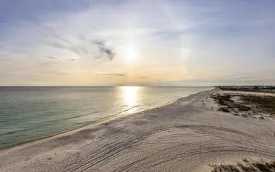 a beach with the sun setting over the water at Top Shellf by Oversee 30A in Carillon Beach