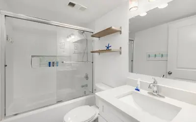 a white bathroom with a toilet and a sink at Top Shellf by Oversee 30A in Carillon Beach