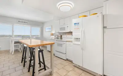 a kitchen with white appliances and a wooden table at Drift on Inn by Oversee 30A in Carillon Beach
