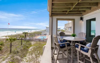 a balcony with a table and chairs and a view of the beach at The Little Round Up by Oversee 30A in Panama City Beach