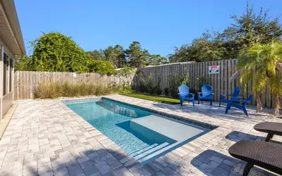 a backyard with a swimming pool with chairs and a fence at Point Three by Oversee 30A in Panama City Beach