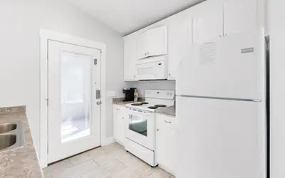 a kitchen with white cabinets and a white refrigerator at Point Three by Oversee 30A in Panama City Beach