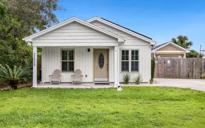 a white house with two chairs in a yard at Point Three by Oversee 30A in Panama City Beach