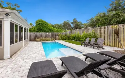 a backyard with a swimming pool with chairs and a fence at Point Three by Oversee 30A in Panama City Beach