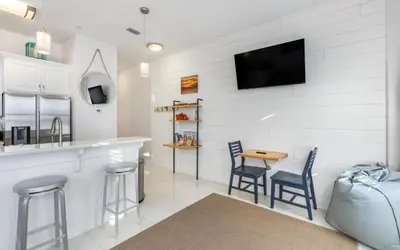a kitchen with a bar and two chairs and a tv at The Sea Goddess by Oversee 30A in Santa Rosa Beach