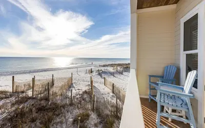 a porch with a blue chair and a view of the beach at The Sea Goddess by Oversee 30A in Santa Rosa Beach