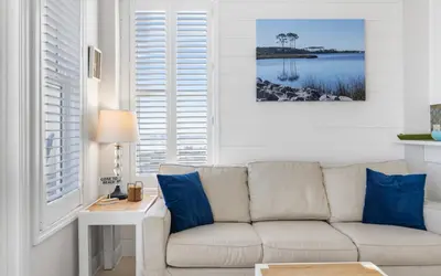 a living room with a white couch and blue pillows at The Sea Goddess by Oversee 30A in Santa Rosa Beach