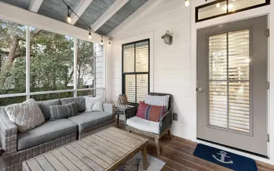 a screened in porch with a couch and a chair at Casa De La Sirena by Oversee 30A in Seacrest