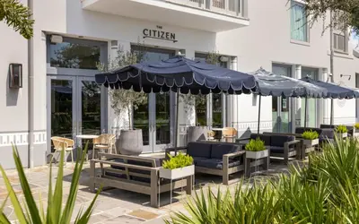 a patio with chairs and umbrellas in front of a hotel at Casa De La Sirena by Oversee 30A in Seacrest