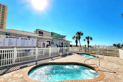 a swimming pool with a fence and a building at -BeachFront Premium-Summit 1124 in Panama City Beach