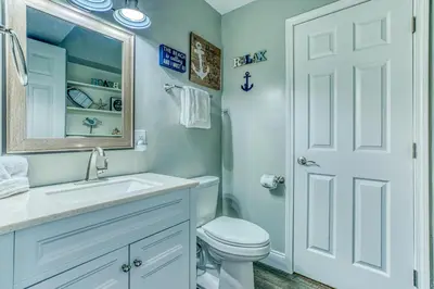 a bathroom with a toilet and a sink and a mirror at -BeachFront Premium-Summit 1124 in Panama City Beach