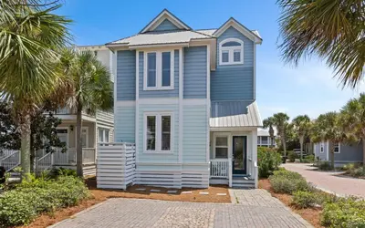 a blue house with palm trees in front of it at Forever and Always by Oversee 30A in Seacrest