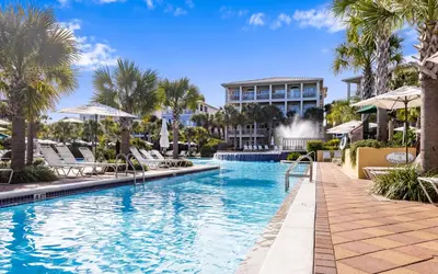 a pool at a resort with chairs and palm trees at Forever and Always by Oversee 30A in Seacrest