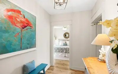 a living room with a red bird painting on the wall at Oasis By The Water by Oversee 30A in Seacrest