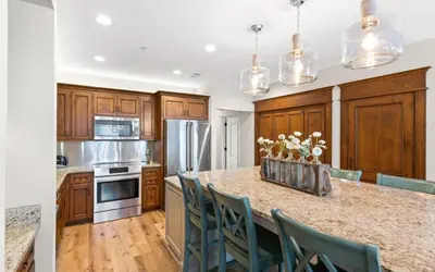 a kitchen with wooden cabinets and a counter with chairs at Oasis By The Water by Oversee 30A in Seacrest