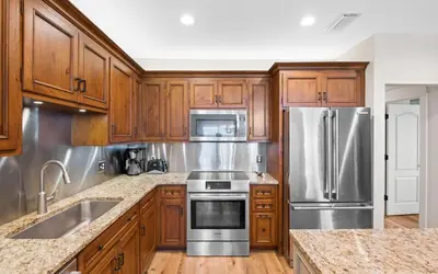 a kitchen with wooden cabinets and stainless steel appliances at Oasis By The Water by Oversee 30A in Seacrest