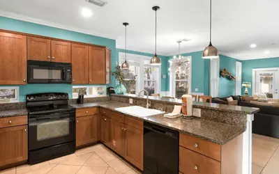 a kitchen with wooden cabinets and black appliances at The Loopy Crab by Oversee 30A in Seacrest