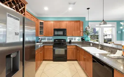 a kitchen with wooden cabinets and black appliances at The Loopy Crab by Oversee 30A in Seacrest