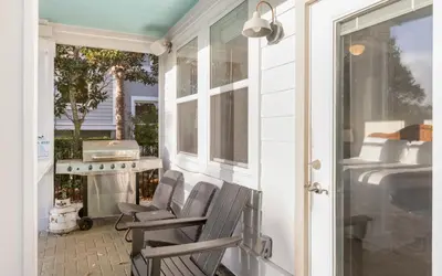 a porch with two chairs and a grill on it at The Loopy Crab by Oversee 30A in Seacrest