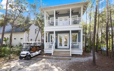 a white house with a golf cart in front of it at Sweet Lu-Sea by Oversee 30A in Santa Rosa Beach