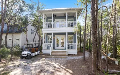 a white house with a golf cart in front of it at Sweet Lu-Sea by Oversee 30A in Santa Rosa Beach