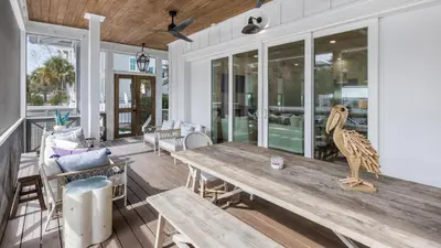 a porch with a wooden table and chairs at Good Times and Tan Lines by Oversee 30A in Santa Rosa Beach