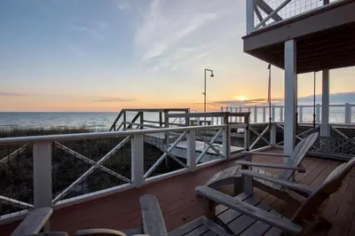 a deck with two chairs and the ocean at sunset at Gone Coastal by Oversee 30A in Santa Rosa Beach
