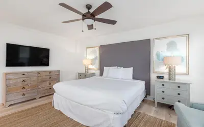 a bedroom with a white bed and a flat screen tv at Brothers Beach Bungalow by Oversee 30A in Santa Rosa Beach