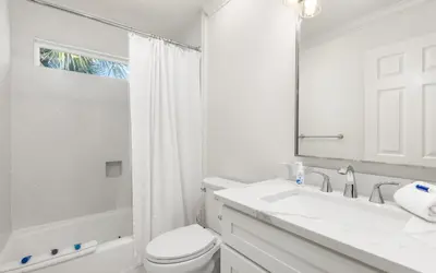 a white bathroom with a toilet and a sink at Brothers Beach Bungalow by Oversee 30A in Santa Rosa Beach
