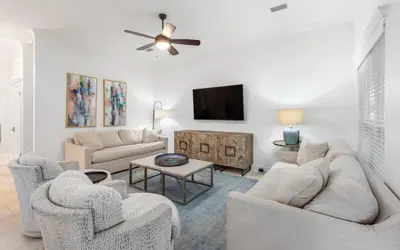 a living room with white furniture and a flat screen tv at Brothers Beach Bungalow by Oversee 30A in Santa Rosa Beach