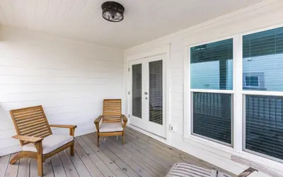 two chairs sitting on a porch with windows at Brothers Beach Bungalow by Oversee 30A in Santa Rosa Beach