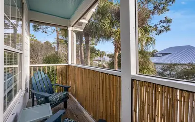 a porch with a blue rocking chair and palm trees at Casa Playa by Oversee 30A in Santa Rosa Beach
