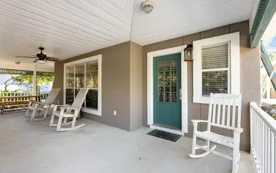 a porch with white chairs and a green door at Clareon By The Coast by Oversee 30A in Seacrest